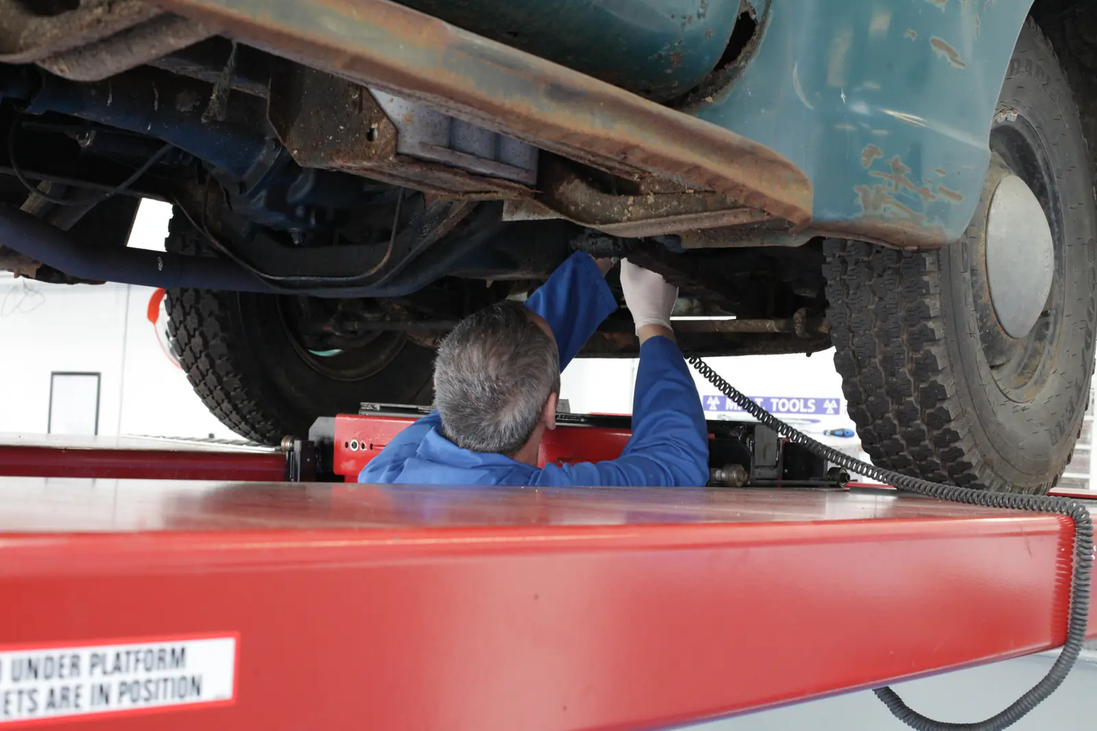 An Albies technician inspecting a vehicle on a lift in the company's MOT workshop